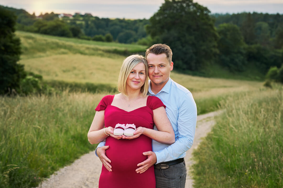 Babybauchfotografie, schwangere Frau in rotem Kleid mit Partner in der Natur, Mandy Limbach Fotografie
