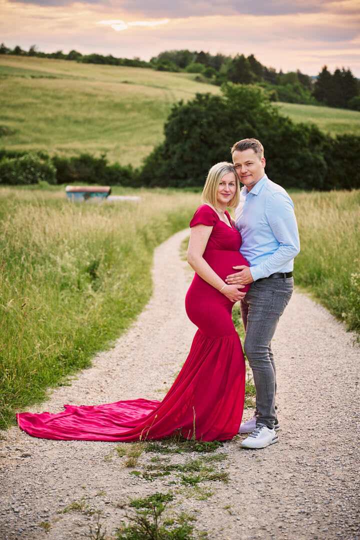 Babybauchfotografie, schwangere Frau in rotem Kleid mit Partner in der Natur, Mandy Limbach Fotografie
