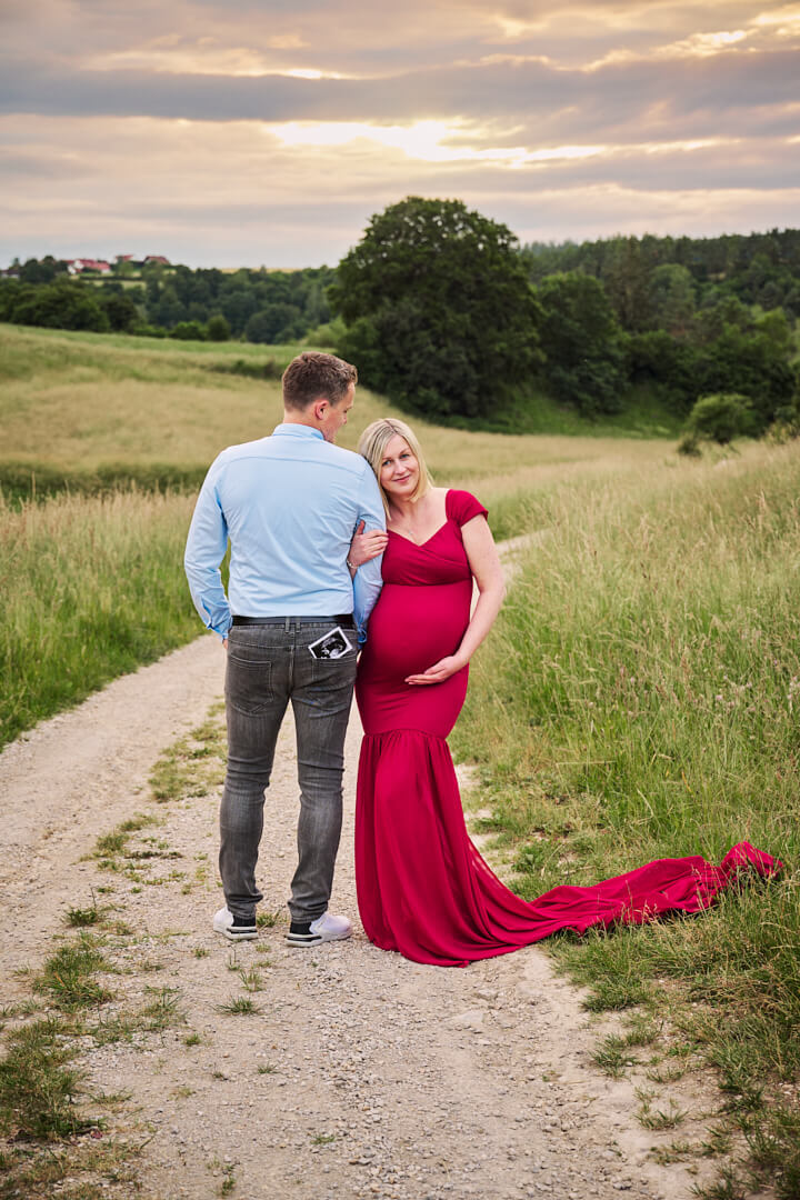 Babybauchfotografie, schwangere Frau in rotem Kleid mit Partner in der Natur, Mandy Limbach Fotografie