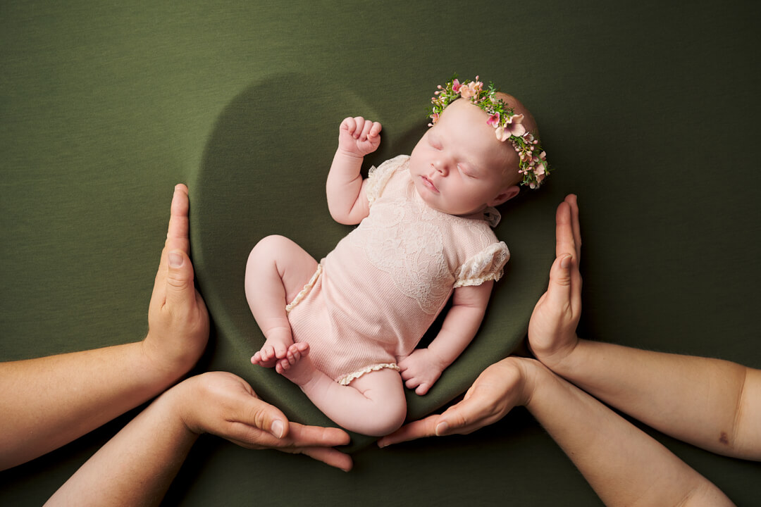 Neugeborenes liegt in Herzschale auf grüner Decke. Eltern halten die Herzschale. Neugeborenenfotos Neugeborenenfotografie Newborn Shooting Babyfotografie Ingolstadt Mandy Limbach Fotografie